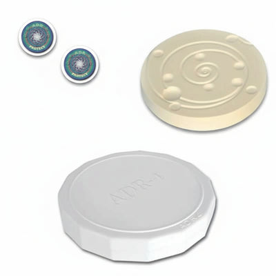 3 different round products, two stickers ADR Protect with swirling pattern, one ADR-3 ivory ceramic disk with swirling pattern, and one ADR-4 white disk