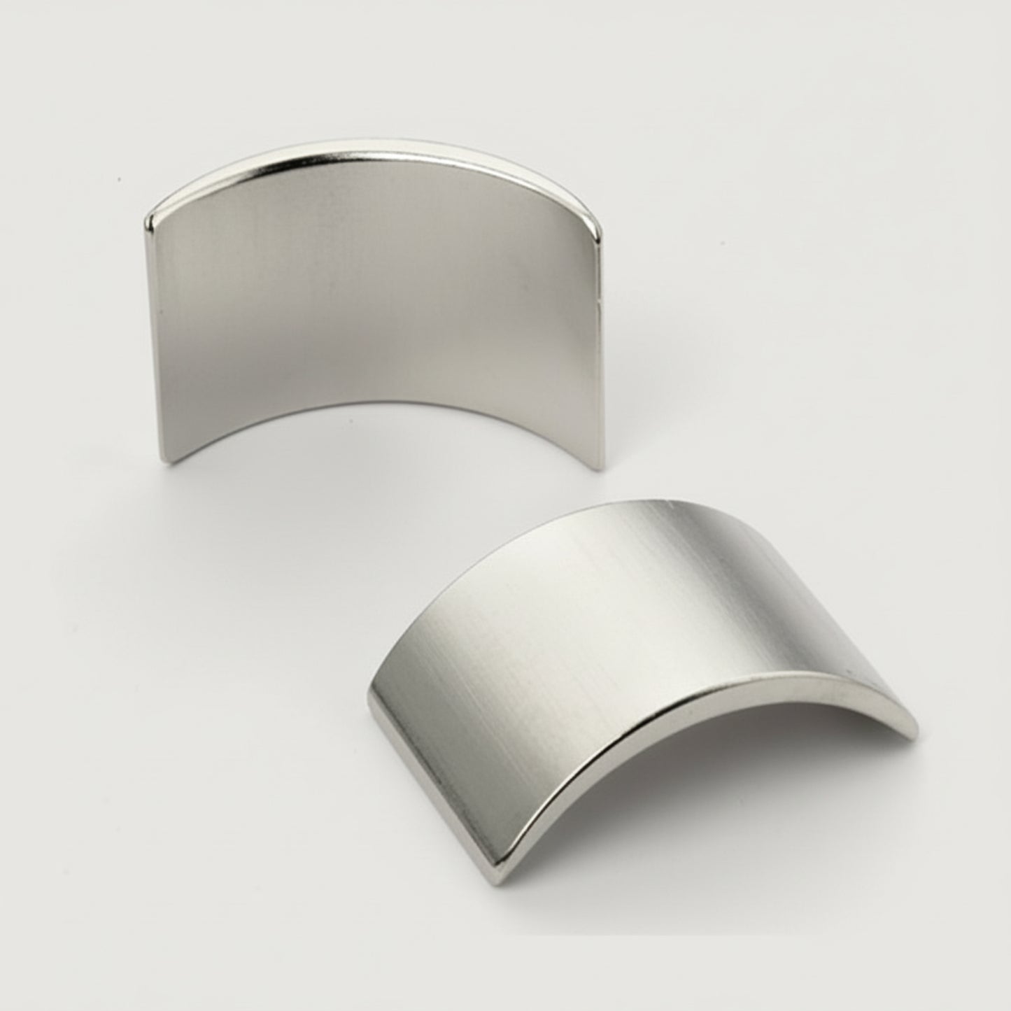 Two metallic half sphere shapes on a light gray background