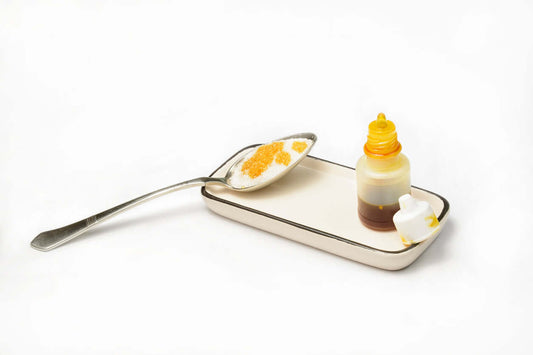 A spoon with propolis and a bottle beside it on a tray, showcasing natural ingredients.
