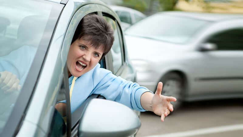 A woman expressing frustration while driving, representing stress related to traffic and the need to Normalize Your Stress Hormones.