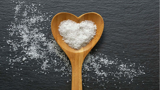 Salt's Vital Functions in Your Body represented in a heart-shaped spoon filled with coarse salt.