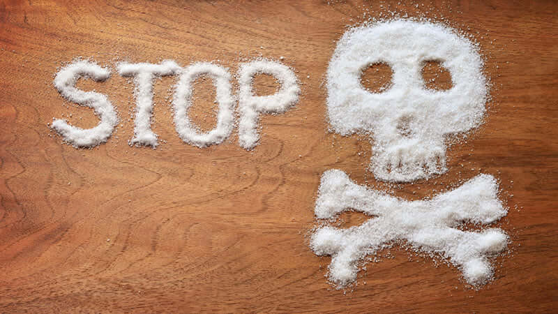 STOP written in sugar with a skull symbolizing the dangers of Cancer and Sugar Addiction.