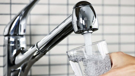 Water filtration is NOT enough; a person pours water from a faucet into a glass.