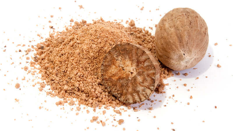 Nutmeg spices with whole nutmeg seeds and ground powder on a white background.