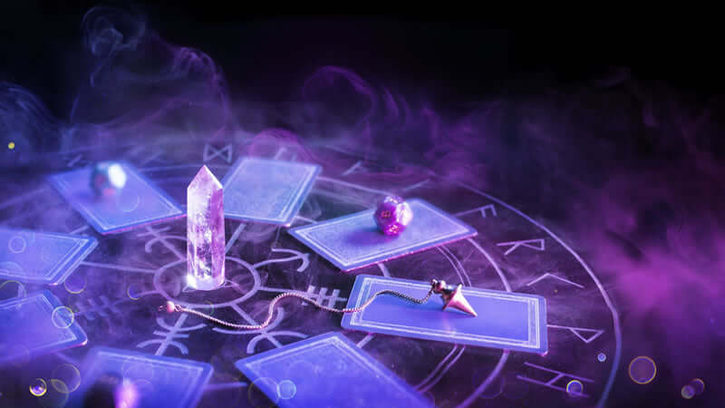 Mystical setup featuring the Philosophers Stone with crystal and tarot cards in a smoky atmosphere.