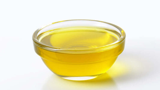 Ratite Oil Ingredients in a clear glass bowl filled with golden yellow oil.
