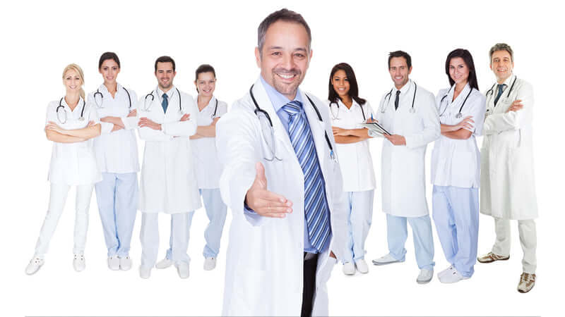 Group of healthcare professionals smiling and posing together in a clinical setting.