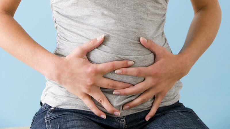 Person holding their stomach, representing Symptoms and Causes of Intestinal Dysbiosis.