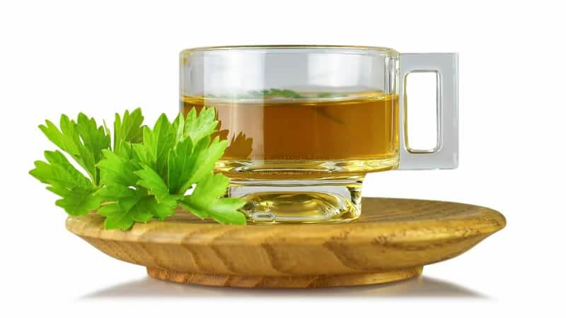 Parsley Tea for Urinary Infections and Kidney Stones in a clear mug with fresh parsley leaves.