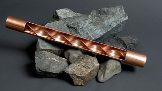 Vortex Water Energizing copper device placed on rocks, showcasing its unique spiral design for energizing water.