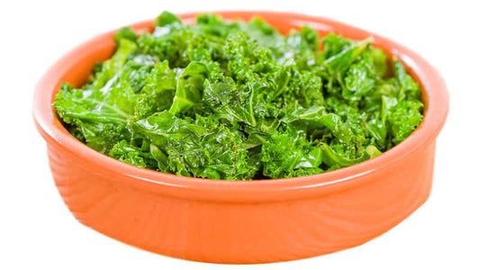 Freshly washed Kale in a vibrant orange bowl, showcasing its rich green color and texture.
