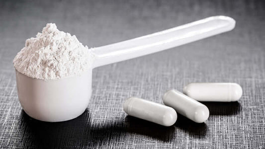 Amino Acids powdered supplement in a scoop with white capsules on a textured background.