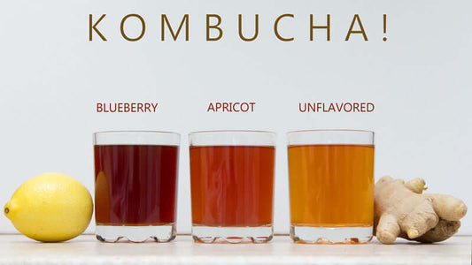 Three glasses of Kombucha flavors: blueberry, apricot, and unflavored, with lemon and ginger.