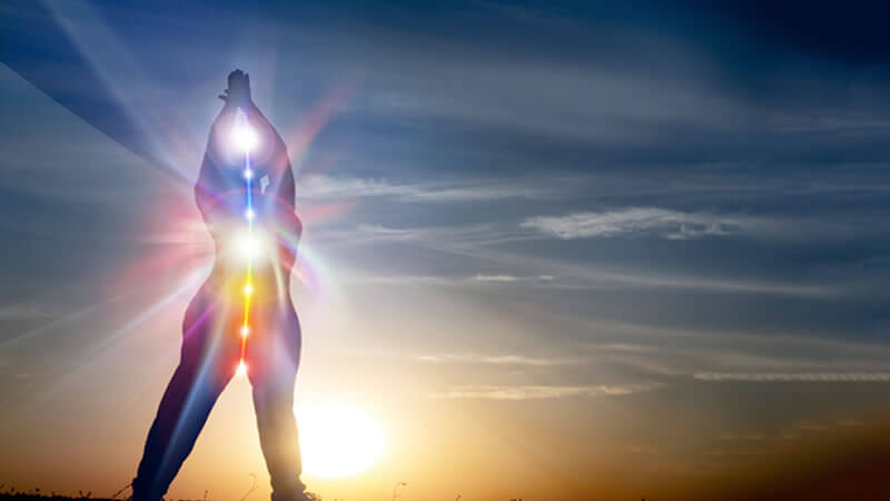 Person standing with outstretched arms against a sunset, radiating Scalar Energy Benefits.