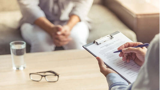 Person discussing Vibrational Medicine during a consultation with a clipboard and glasses on the table.