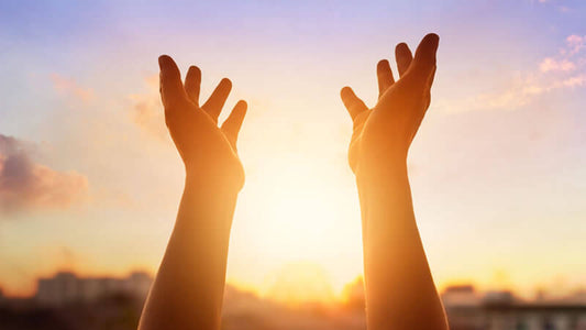 Hands reaching towards the sun during light therapy, symbolizing Anodyne or Light Therapy.