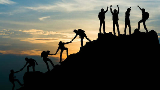 About Us at Life Enthusiast - people climbing a mountain together, symbolizing teamwork and support.