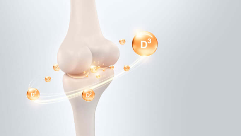 Illustration of a knee joint with Vitamin D3 particles, highlighting Vitamin D's importance for bone health.