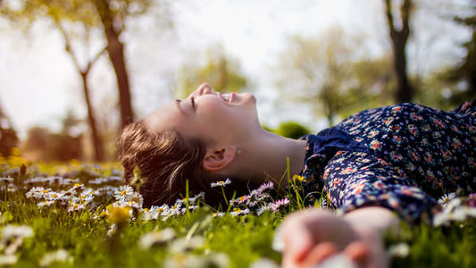 Woman enjoying nature while lying in flowers, embodying the concept of Nutrition from Sunlight.