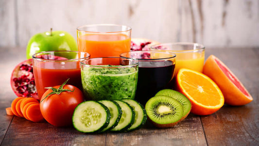 Colorful array of superfood blends in glasses with fresh fruits and vegetables on a wooden table.