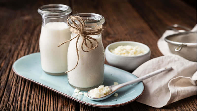 Kefir Probiotic Jewel in glass bottles with fresh grains on a blue plate, showcasing the healthy beverage.