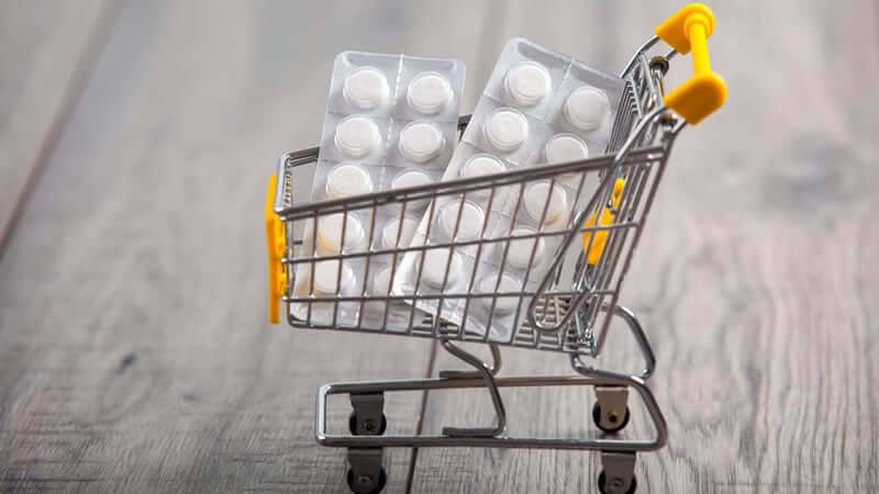 Pharmaceuticals Cause Magnesium Deficiency depicted in a shopping cart filled with medicine packs.