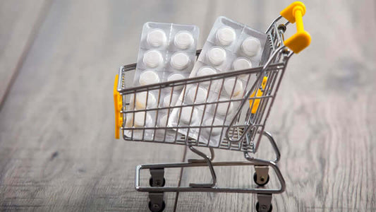 Pharmaceuticals Cause Magnesium Deficiency depicted in a shopping cart filled with medicine packs.