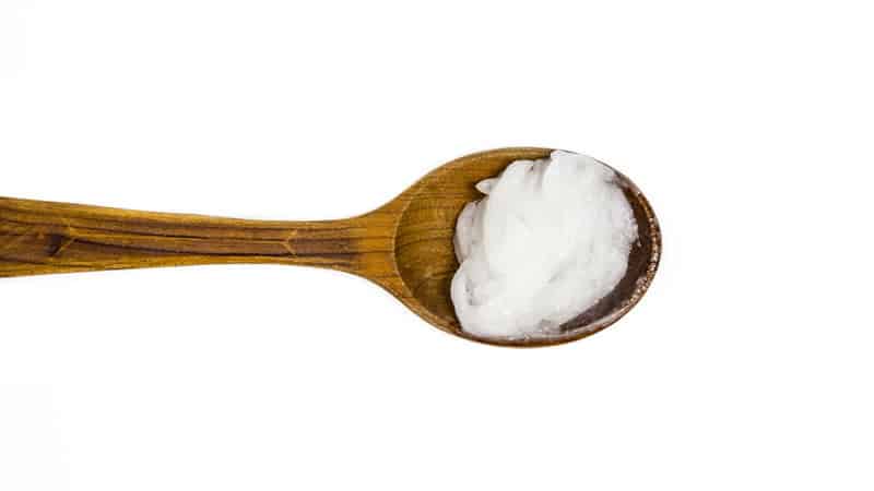 Coconut Oil in a wooden spoon, showcasing its texture for weight loss reviews.