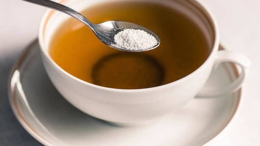 A teaspoon of artificial sweetener over a cup of herbal tea, highlighting evils in aspartame consumption.