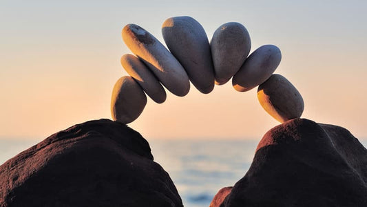 ORMUS and Importance of Mineral Balance depicted by balanced stones at sunset.
