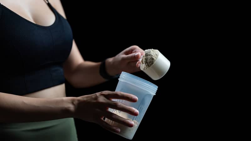A person measuring whey protein powder to mix, illustrating the topic of Weighing Up Whey.