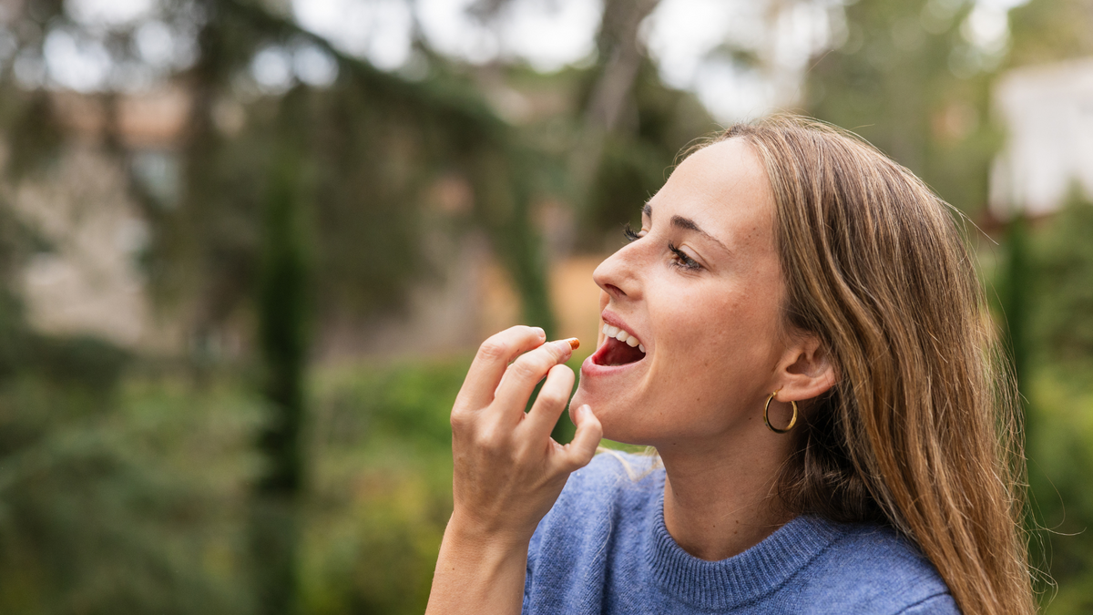 Woman taking a natural antiviral supplement outdoors to support her immune system