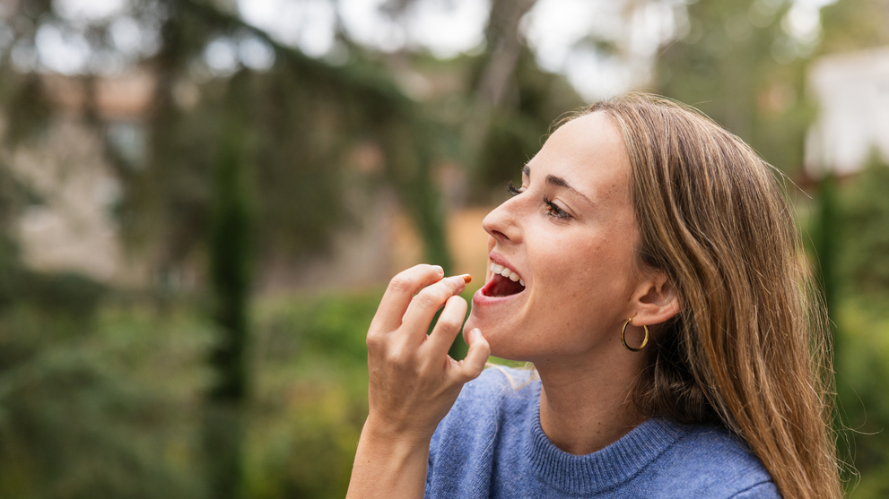 Woman taking a natural antiviral supplement outdoors to support her immune system