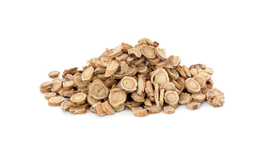 Dried Astragalus root slices piled on a white background, showcasing their texture and shape.