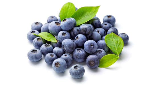Fresh blueberries with green leaves piled together, showcasing the vibrant color and texture of blueberries.