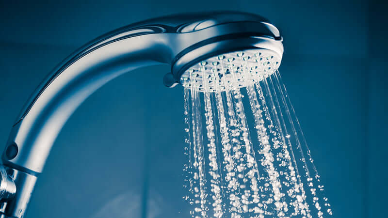 Chlorinated Water Health Hazards: Close-up of a showerhead spraying water.