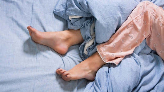 Feet on a bed representing discomfort caused by Restless Legs Syndrome.