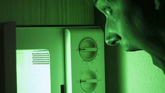 Person looking anxiously at a microwave, illustrating concerns about Microwaved Food Harmful Effects.