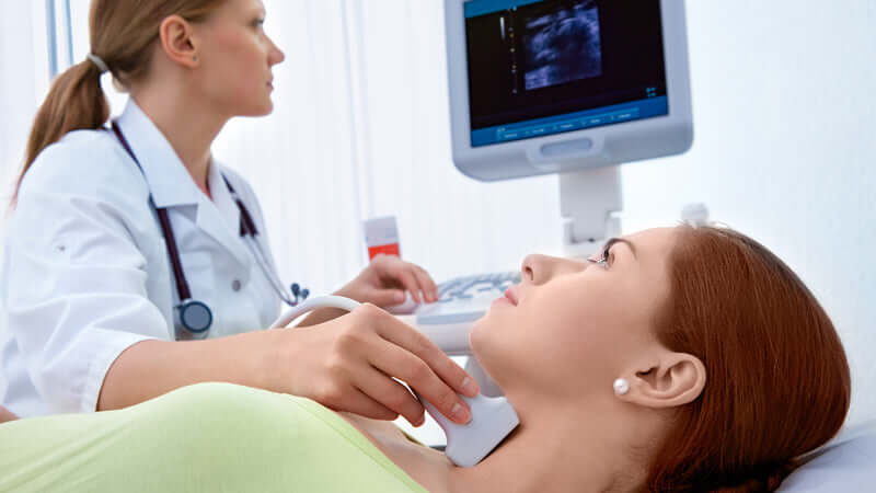 A healthcare professional performing a thyroid ultrasound to check for Iodine Deficiency Effects.