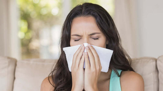 Woman using tissue while suffering from allergies, emphasizing how salt spray stops germ spread.