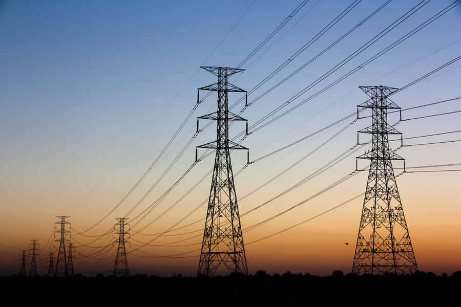 Power lines silhouetted against a sunset sky, illustrating EMF Protection Basics.