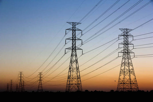 Power lines silhouetted against a sunset sky, illustrating EMF Protection Basics.