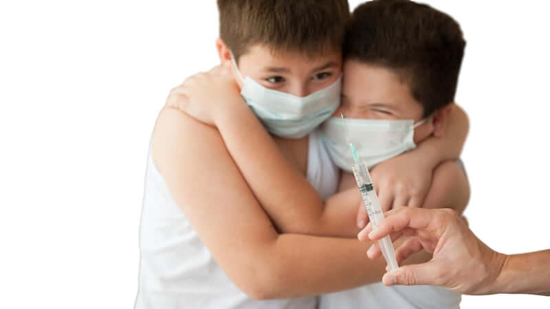 Children wearing masks show concern as they face a Vaccine Alert situation with a syringe presented nearby.