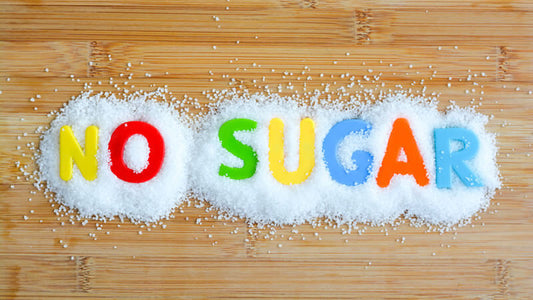 Colorful letters spelling 'NO SUGAR' on white sugar, emphasizing the message that refined sugar is not healthy.