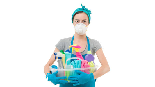 Household Cleaners can Make You Sick: person wearing mask and gloves holding a basket of cleaning products