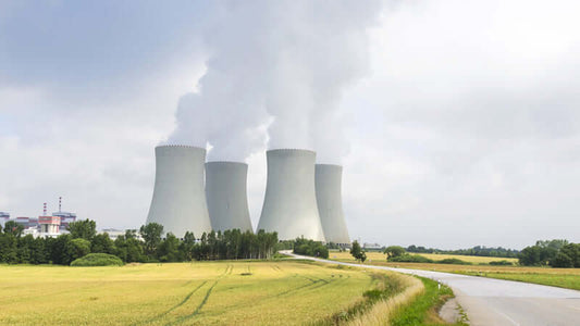 Nuclear power plant cooling towers emitting steam in a rural landscape.