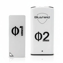 two white devices look like cell phones  for EMF protection, one says Φ1 Blushield, the other says Blushield Φ2