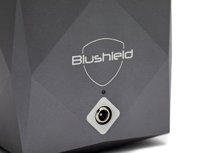 Close-up of a dark gray Blushield electronic device with a white shield logo and a circular port on a white background.