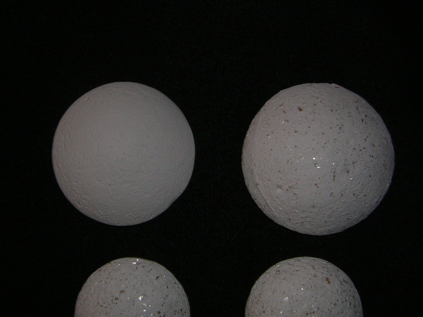 Image of four white spherical objects resembling Crystal Pearls on a black background.