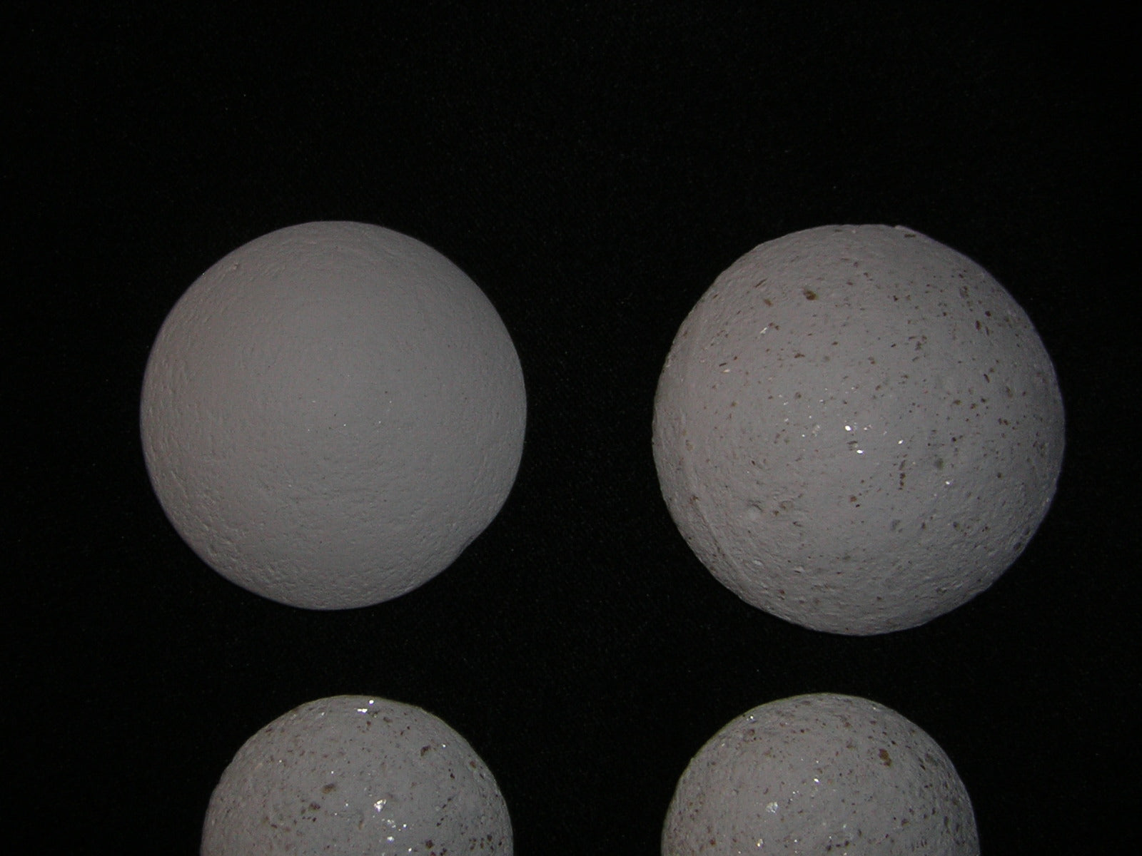 Image of four white spherical objects resembling Crystal Pearls on a black background.